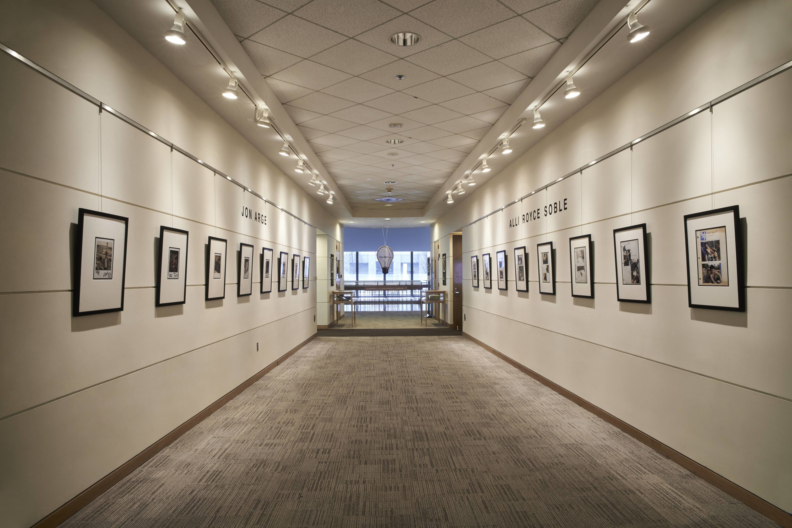 "Our Archives Could Be Your Life" exhibit corridor featuring walls lined with framed Polaroid photographs and scrapbook pages