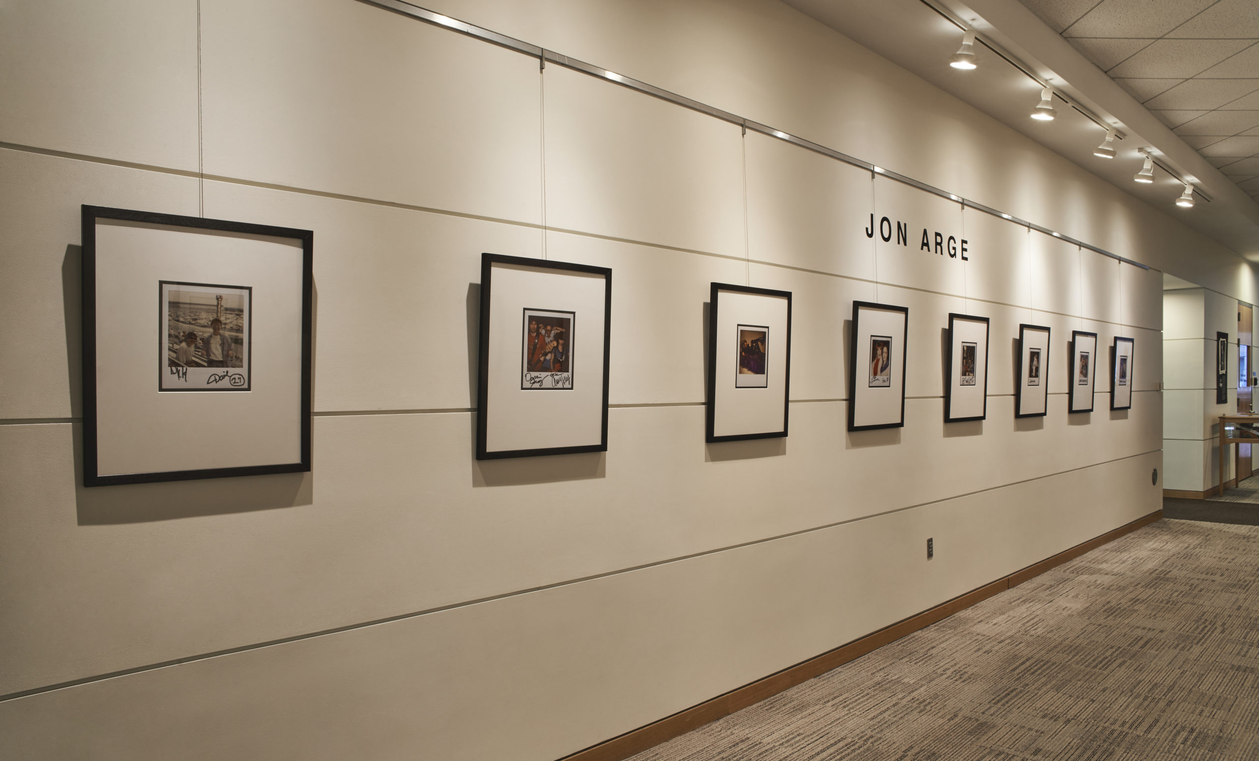 Photograph of exhibit corridor walls filled with framed Jon Arge Polaroid photographs