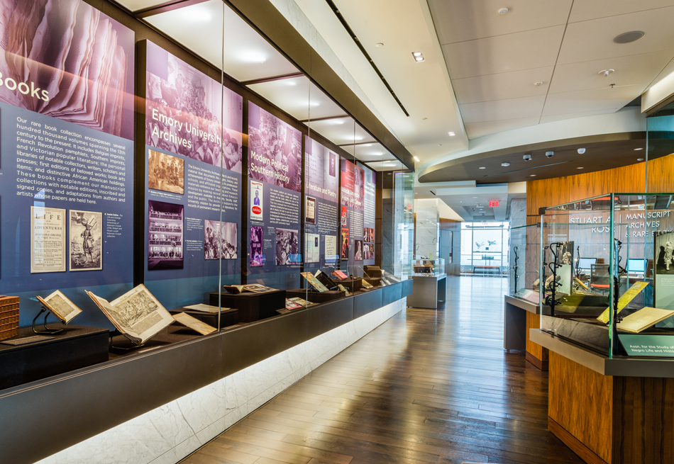 Photograph of exhibit space with glass display cases featuring books, images, and descriptive text