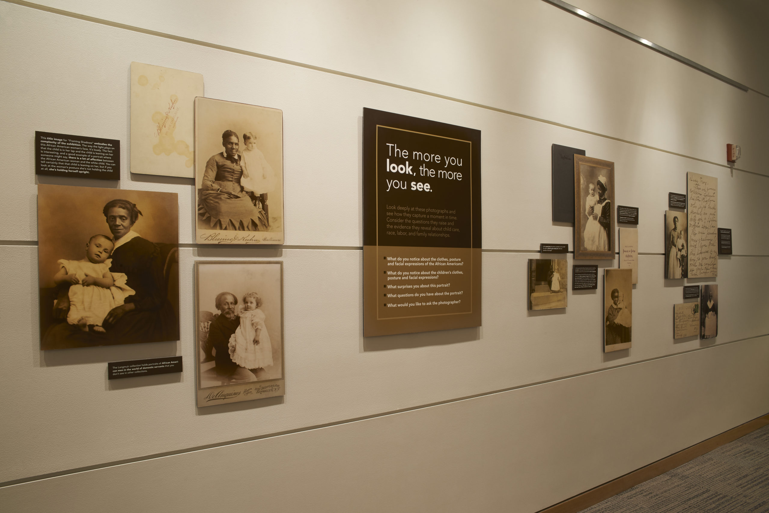 Photograph of exhibit corridor walls filled with photo portraits and text