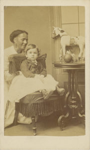 Photograph of woman with medium-dark skin tone posed with infant with light skin tone
