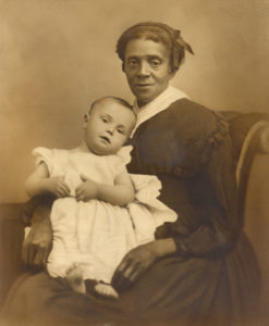 Photograph of child with light skin tone being held by woman with medium-dark skin tone.