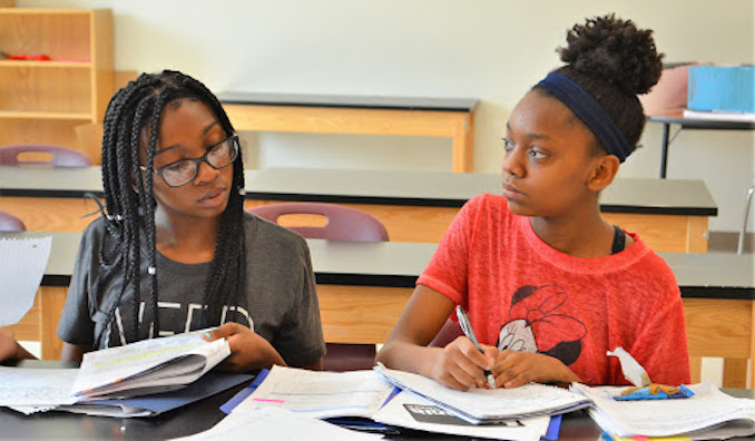 Two young students read and take notes in a classroom