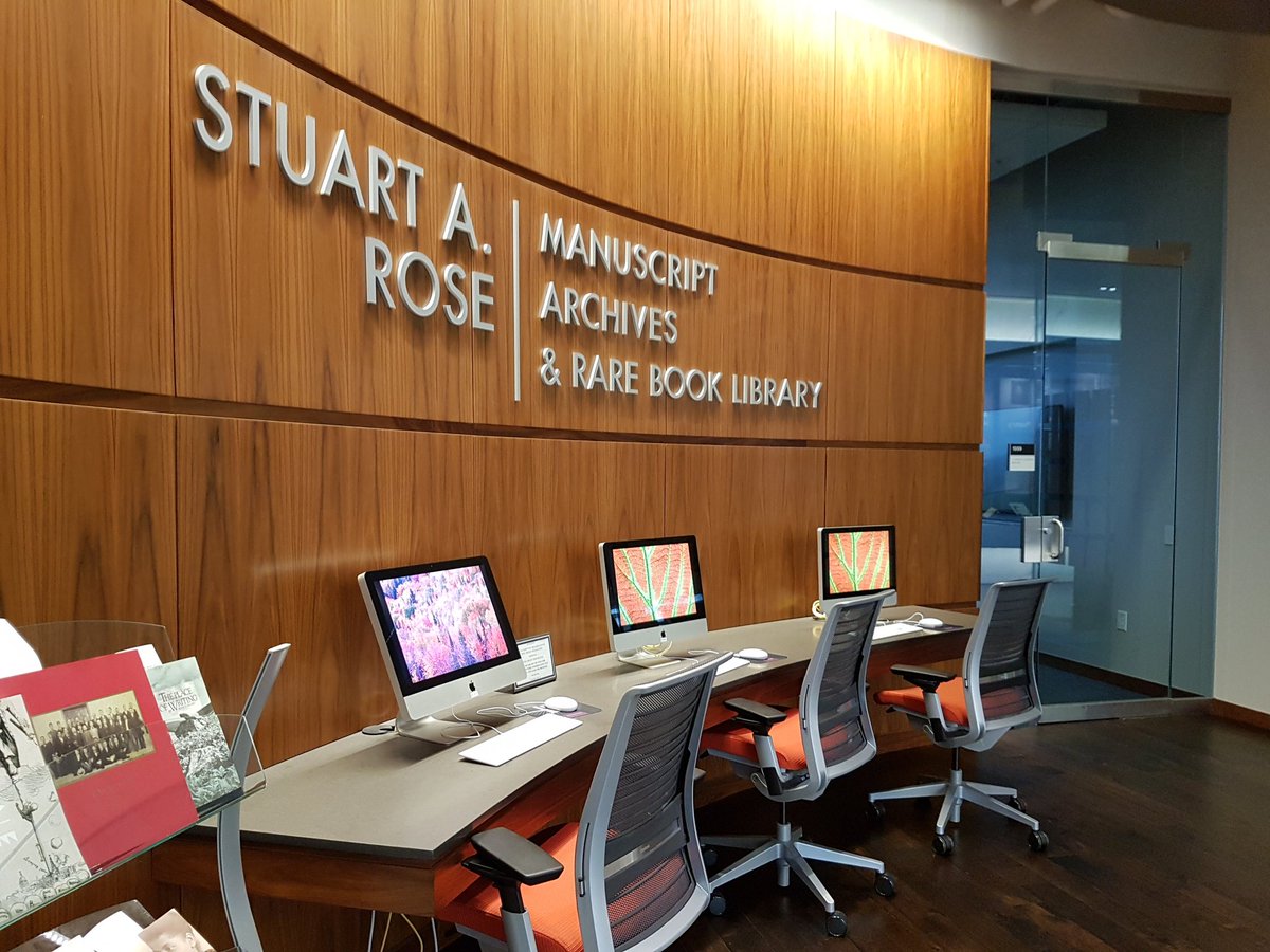 Desk with three computers and chairs in front of curved wooden wall in Rose Library