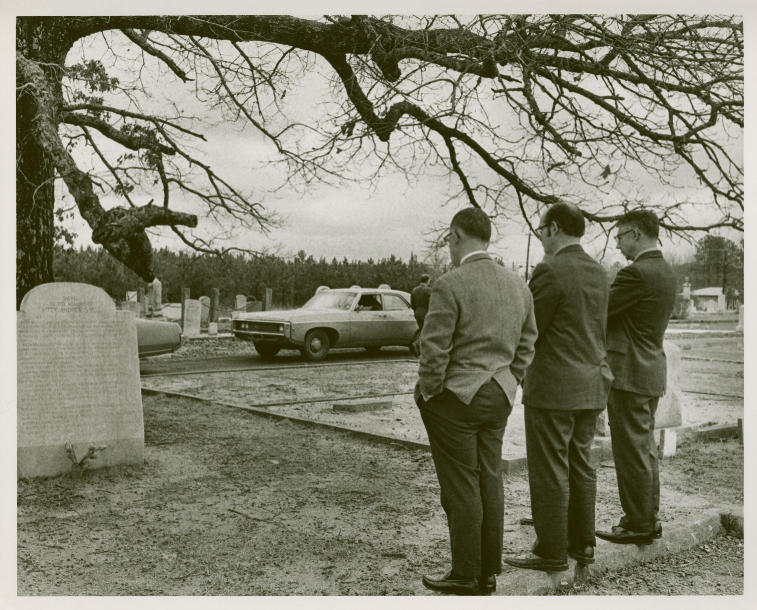 Three men in front of monument to Catherine Boyd in Oxford Historical Cemetery.